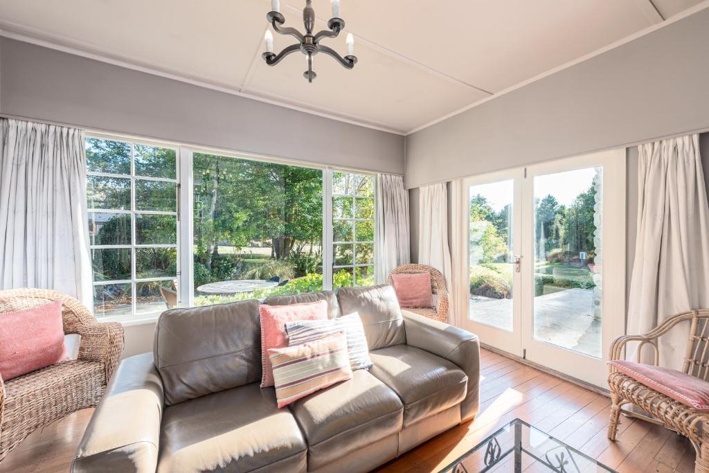特卡波湖约翰山家园度假屋的客厅设有真皮沙发和窗户。