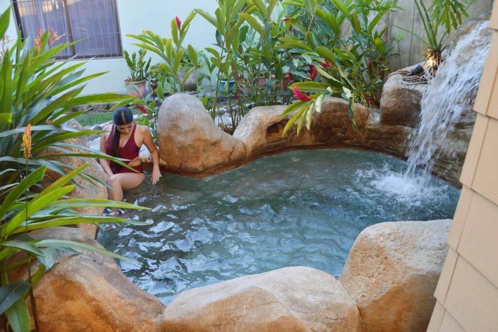 福尔图纳Elegant Villa in La Fortuna with spacious backyard plus very private pool & parking的坐在花园瀑布旁的女人