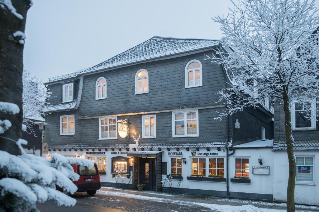 温特贝格Hotel Kiepenkerl的一座大型木结构建筑,在一条雪 ⁇ 的街道上设有商店
