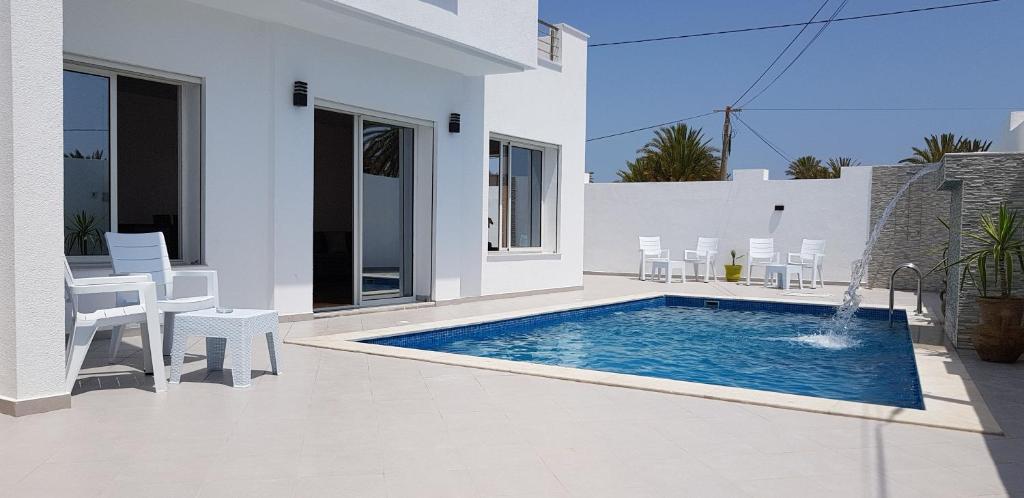 米多恩Villa Aline Lagune Djerba的一座白色的房子,在院子里设有游泳池