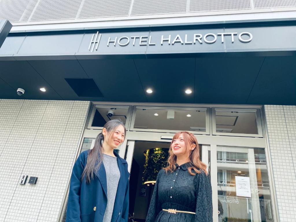 福冈Hotel Halrotto Fukuoka Hakata的两名妇女站在旅馆外