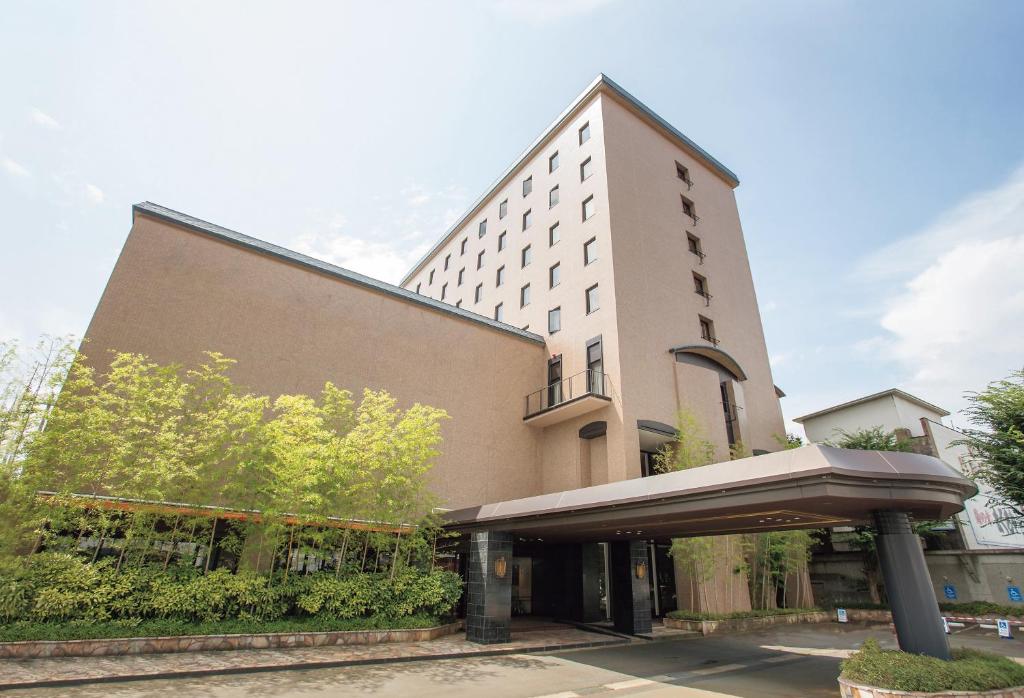 米泽市Yonezawa Excel Hotel Tokyu Reopening on June 1 "DEN'S HOTEL yonezawa"的前面有一把伞的大型白色建筑