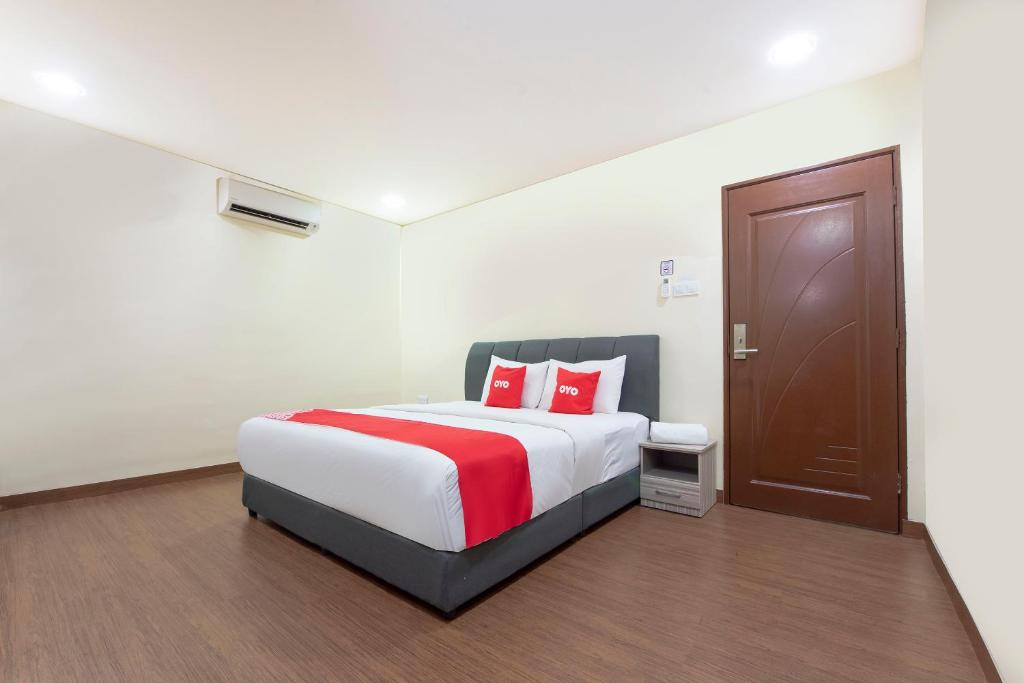 JasinOYO 90380 Hotel Jasin的一间卧室配有一张带红色枕头的大床