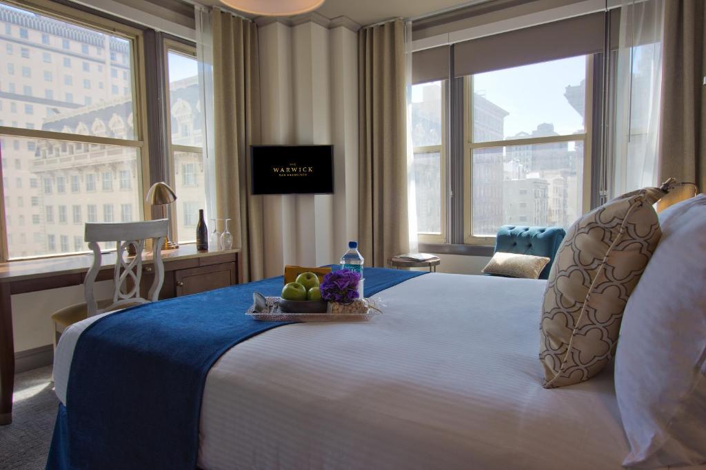 旧金山旧金山沃里克酒店的一间酒店客房,配有一张床铺,上面装有水果盘