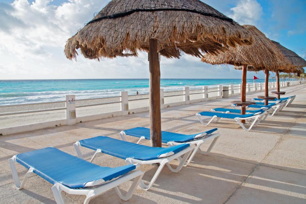 坎昆Perfect vacation getaway,Ocean View,Wifi, Beach的海滩上的一排椅子和遮阳伞