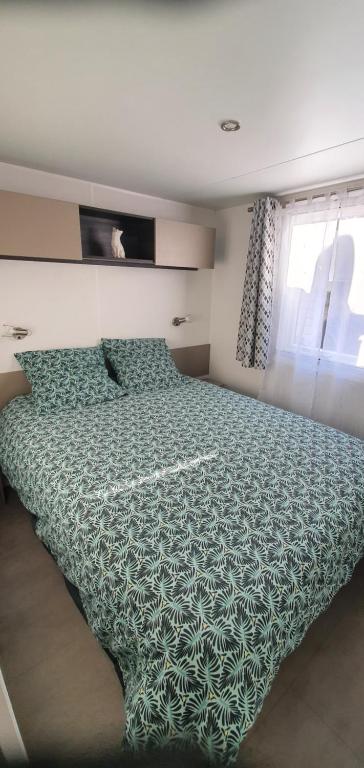 圣让-德蒙MH 149 4 pers camping Bois Dormant confort et détente的一间卧室配有一张带绿色棉被的床和窗户。