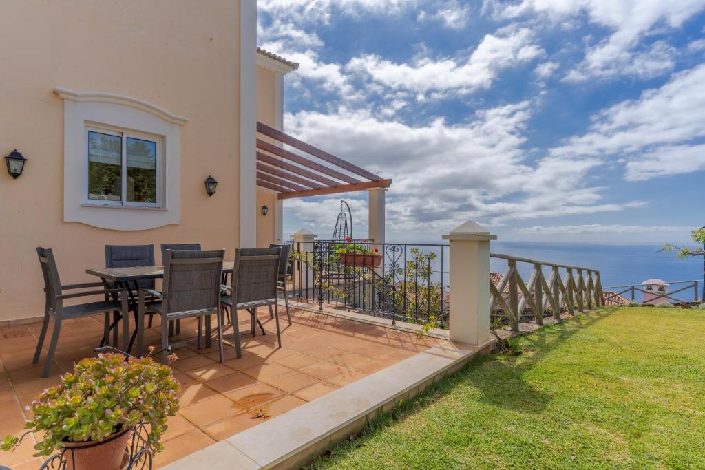 丰沙尔Villa Bougainvillea Palheiro Village by HR Madeira的房屋设有带桌椅的阳台