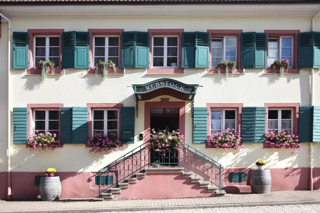苏尔茨堡Landgasthof Rebstock的一座拥有粉红色和绿色百叶窗和楼梯的建筑