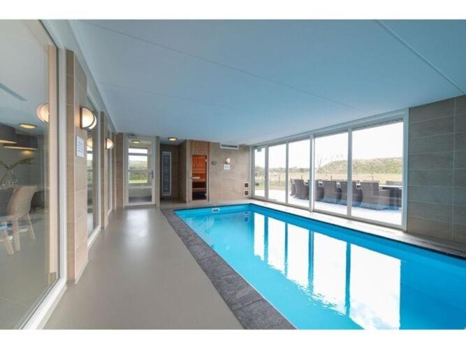 科莱恩斯普拉特Luxury holiday home in Colijnsplaat的蓝色建筑中的一个大型游泳池
