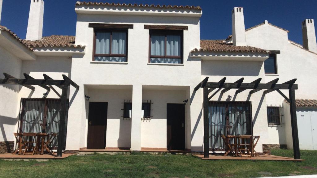 塞维利亚Casa Rural El Olivar的前面有椅子的白色房子