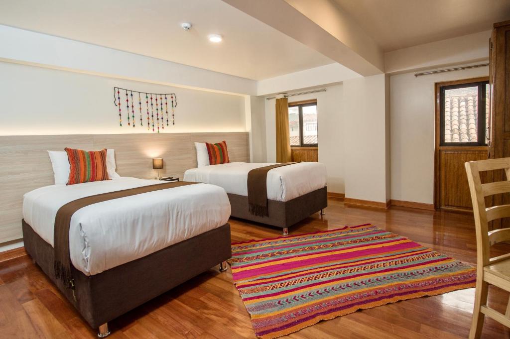 库斯科Casa Matara Boutique的配有地毯的客房内的两张床