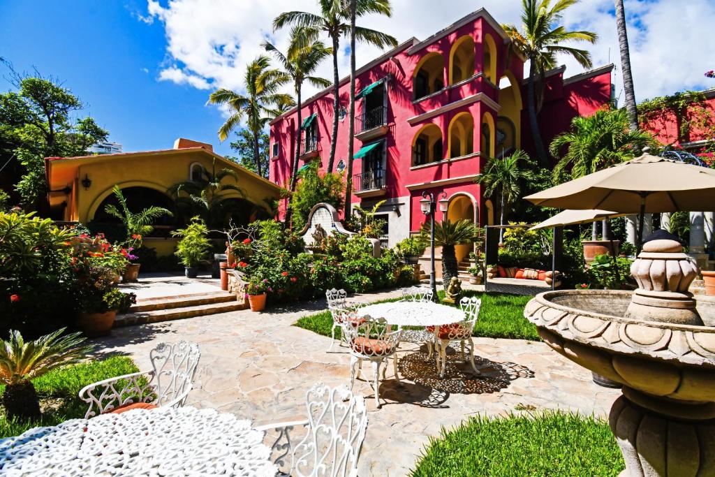 卡波圣卢卡斯Collection O Casa Bella Hotel Boutique, Cabo San Lucas的粉红色的房子,设有喷泉和桌椅
