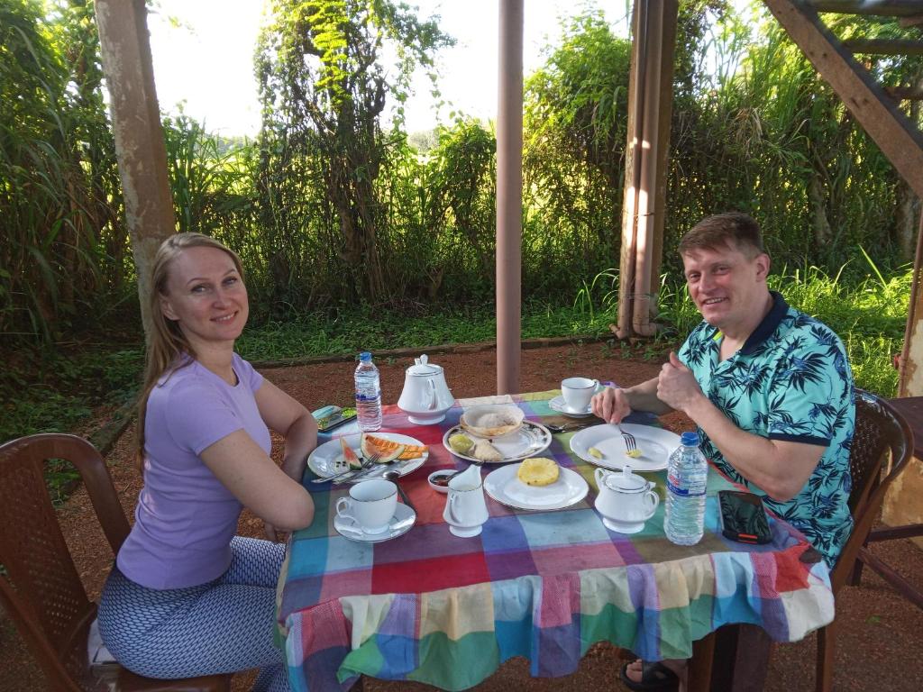 锡吉里亚Sigiriya Paddy Field Hut的坐在餐桌旁吃饭的男人和女人