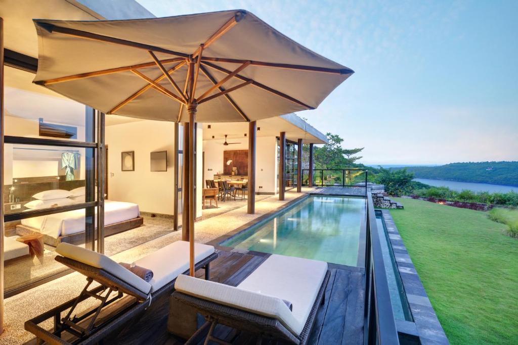 珀尼达岛MAUA Nusa Penida Bali的一个带游泳池和遮阳伞的户外庭院