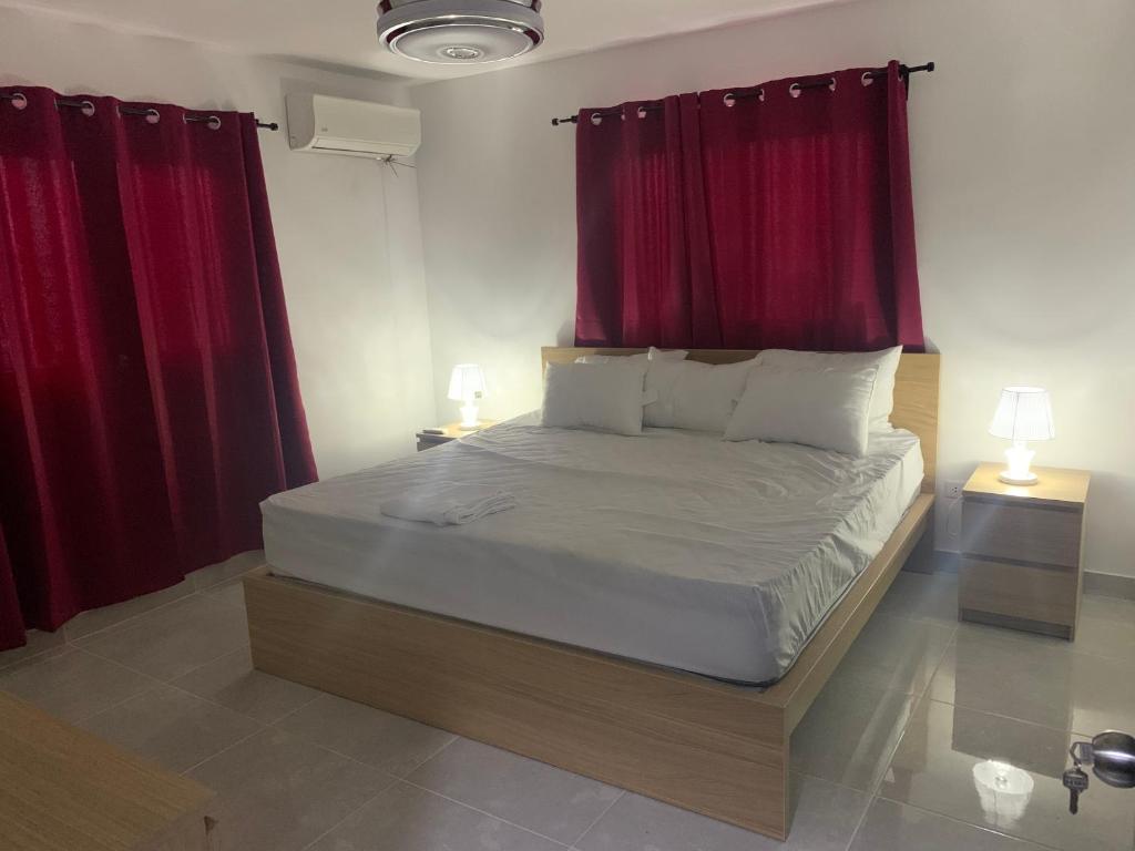 圣多明各3bed Apartment con Terraza y Picsina privada的一间卧室配有一张带红色窗帘的大床
