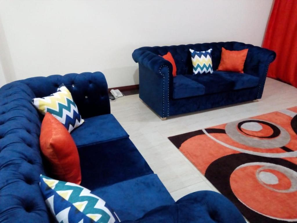 蒙巴萨Lux Suites Royal Family Apartment Nyali的客厅配有2张蓝色的沙发和地毯。