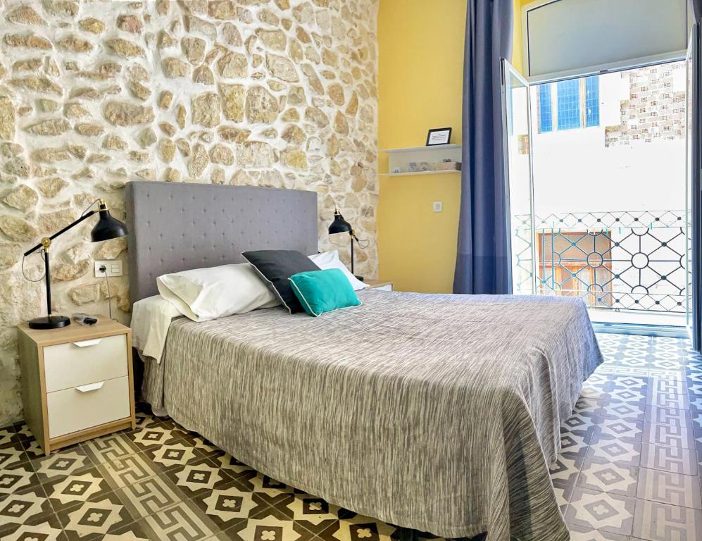 阿利坎特Pensión Alicante San Nicolás的一间卧室设有一张床和石墙