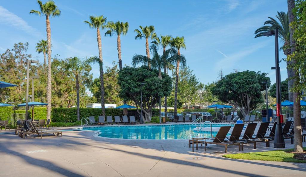 安纳海姆Sonesta ES Suites Anaheim Resort Area的一个带椅子和棕榈树的度假村游泳池