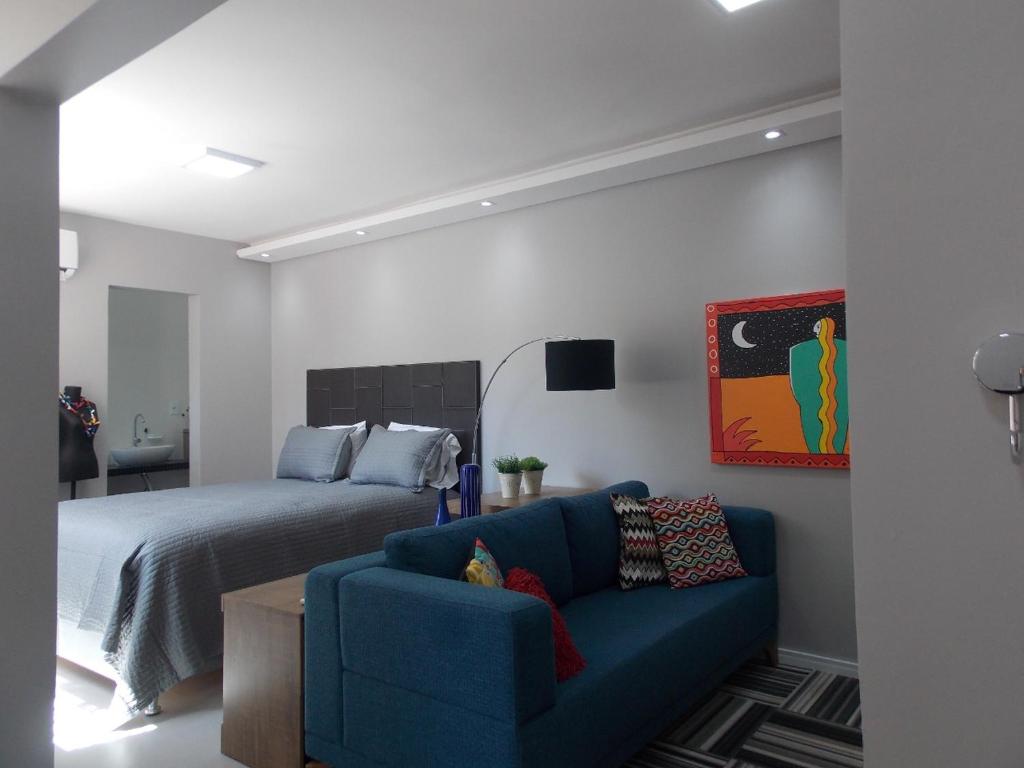 阿雷格里港Apt excelente local Consulado/Iguatemi的一间卧室配有一张床和一张蓝色的沙发