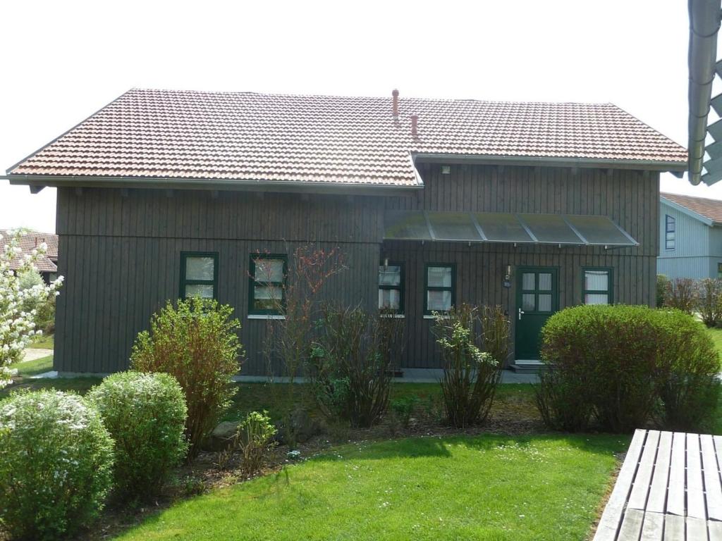 瓦尔德明兴Ferienhaus Nr 16B2, Feriendorf Hagbügerl, Bayr Wald的一间有棕色屋顶和灌木的房子