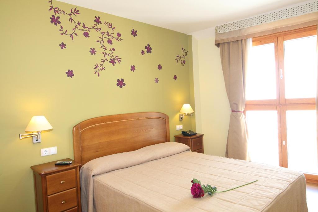 坎波雷亚尔坎普里尔住宿加早餐旅馆的卧室配有一张墙上紫色鲜花的床