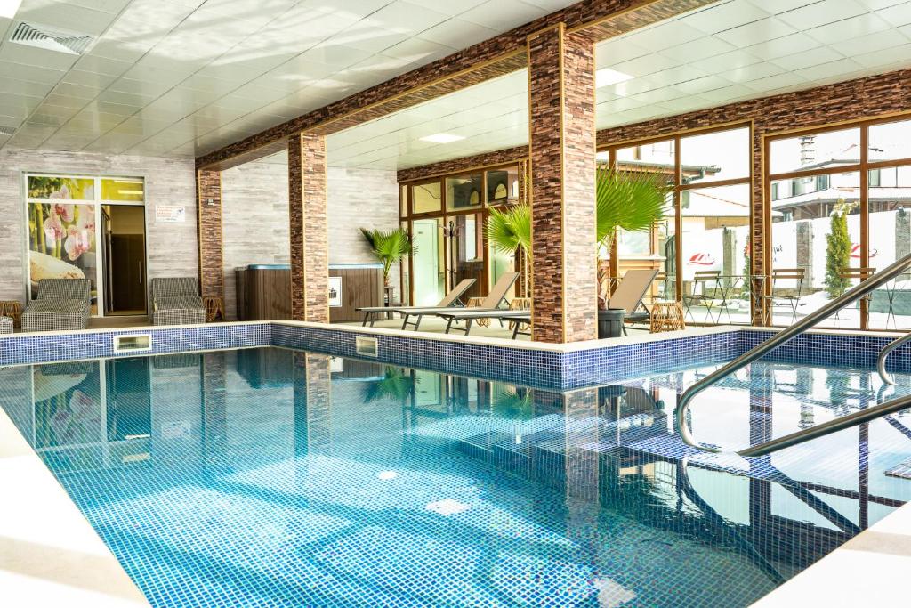 韦林格勒Zarevata Guest House的游泳池铺有蓝色的瓷砖地板,设有窗户。