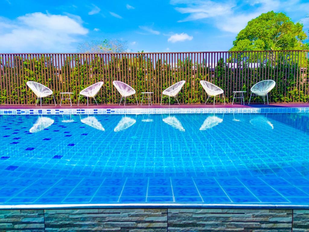 尖竹汶Lueangchan Orchid Hotel的一个带椅子和围栏的游泳池以及一个游泳池