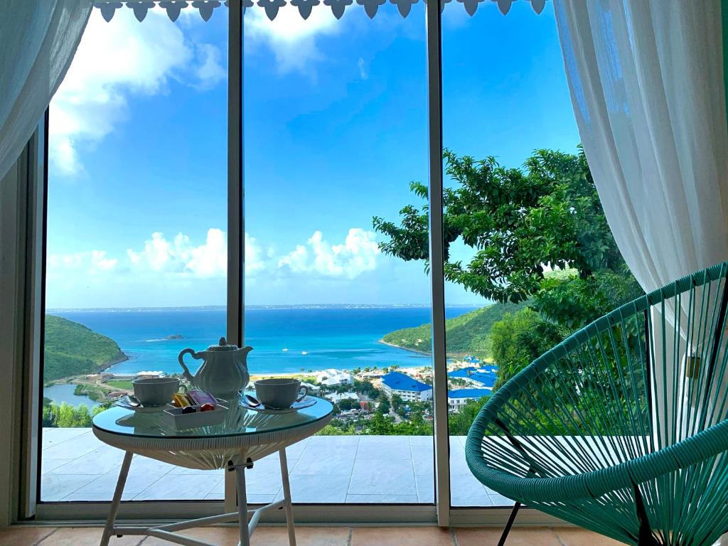 Anse Marcel Villa Privilege的桌子,茶壶和椅子,窗前