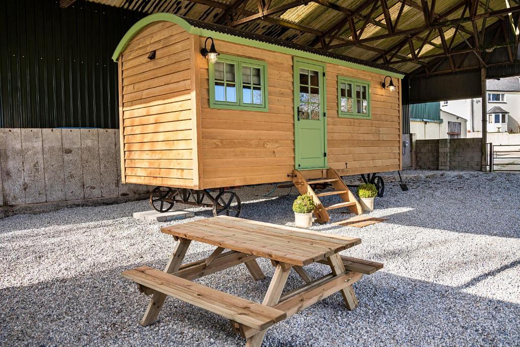 比沃辛Finest Retreats - The Shepherd's Hut at Northcombe Farm的一个小房子,配有野餐桌和长凳