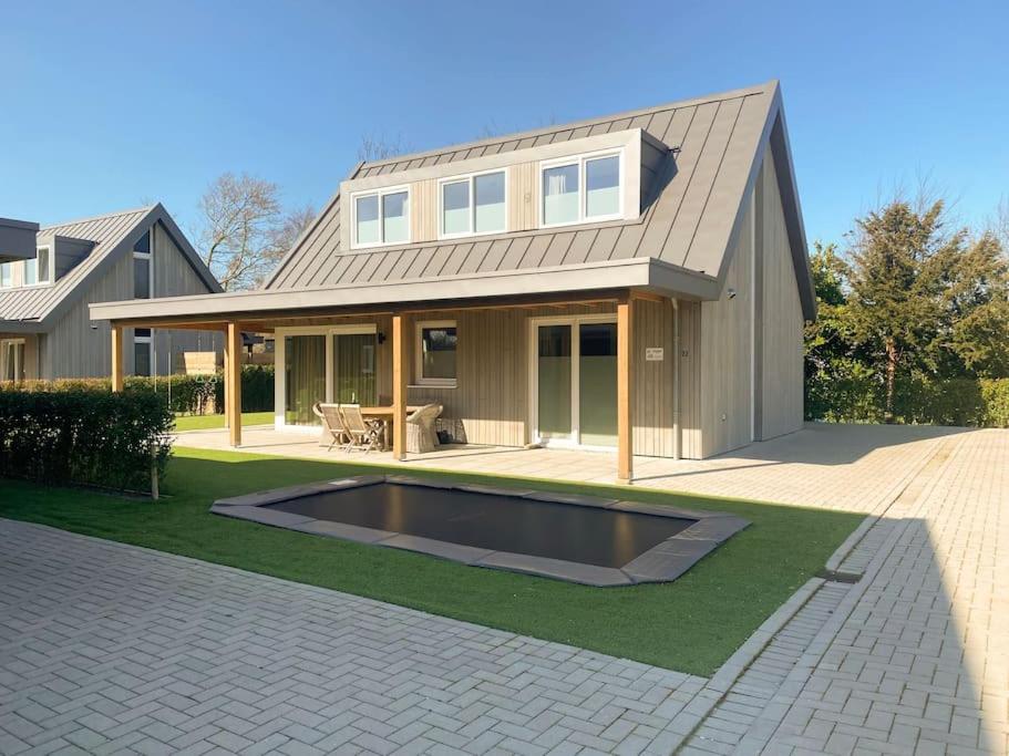 坎珀兰luxe Villa Maroma Regal aan Veerse meer met 4 Ebikes GasBBQ & EV laadpaal的庭院中带游泳池的房子