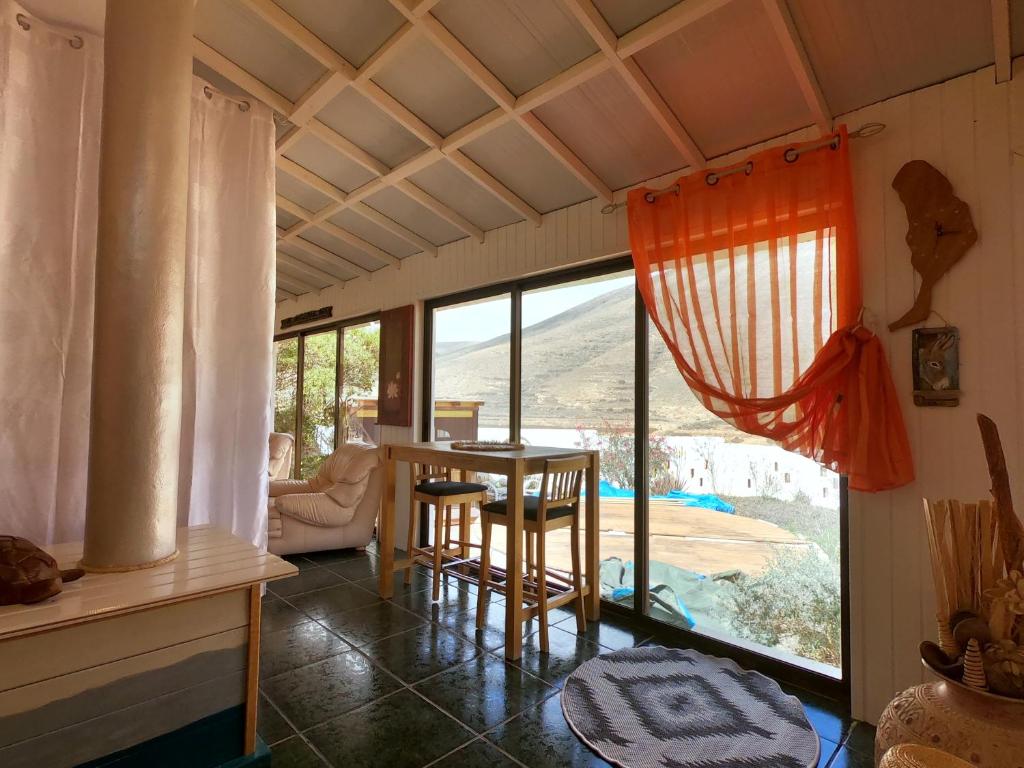 罗萨里奥港Kikiki House的客房设有桌椅和大窗户。