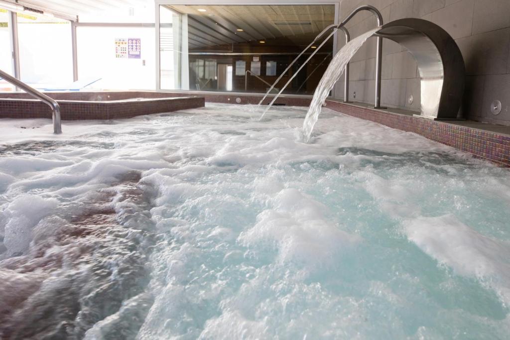 比韦罗Hotel Thalasso Cantabrico Las Sirenas 4 Superior的一座建筑里装满雪的按摩浴缸