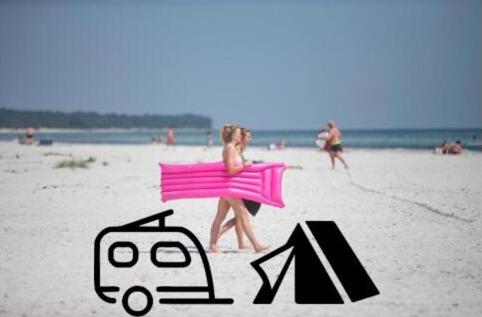 DueoddeDueodde Strand Camping的穿粉红色衣服的女人在海滩上散步