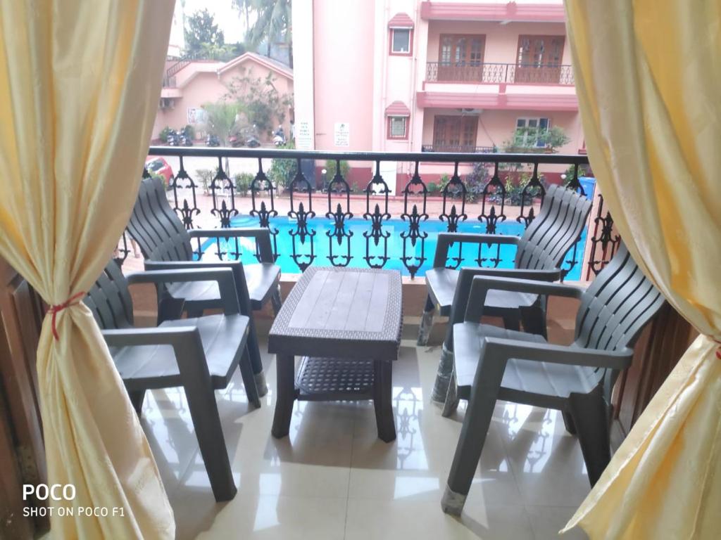 卡兰古特2 bhk Calangute - Baga road Saldanha Kyle Gardens的一个带桌椅的阳台和一个游泳池