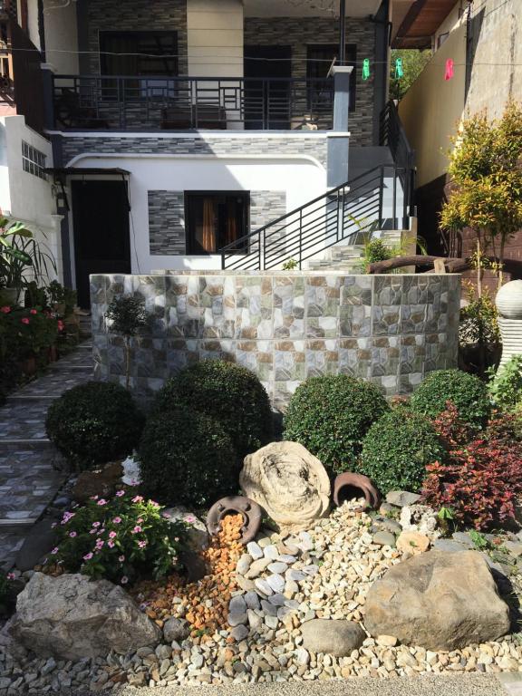 碧瑶拉法米尔旅馆的一座花园,位于一座拥有岩石和植物的房子前
