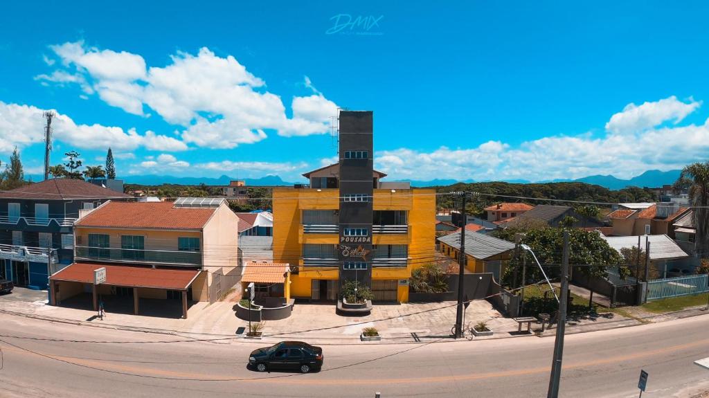 瓜拉图巴Pousada Estrela Dourada的一条城市街道上一座黄色建筑,有钟楼
