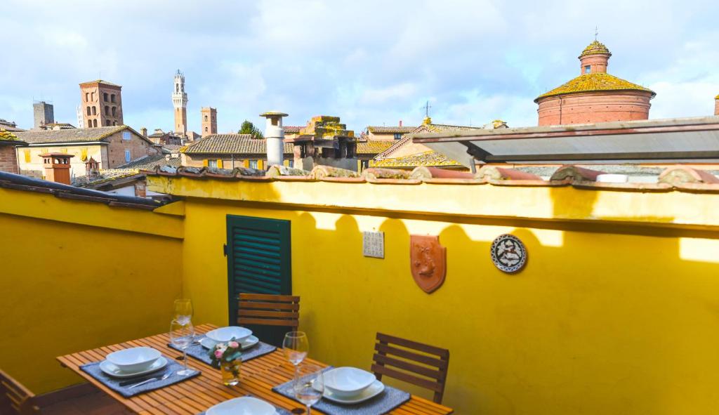锡耶纳Un terrazzo sulla magia的黄色的房子,上面有桌子和盘子
