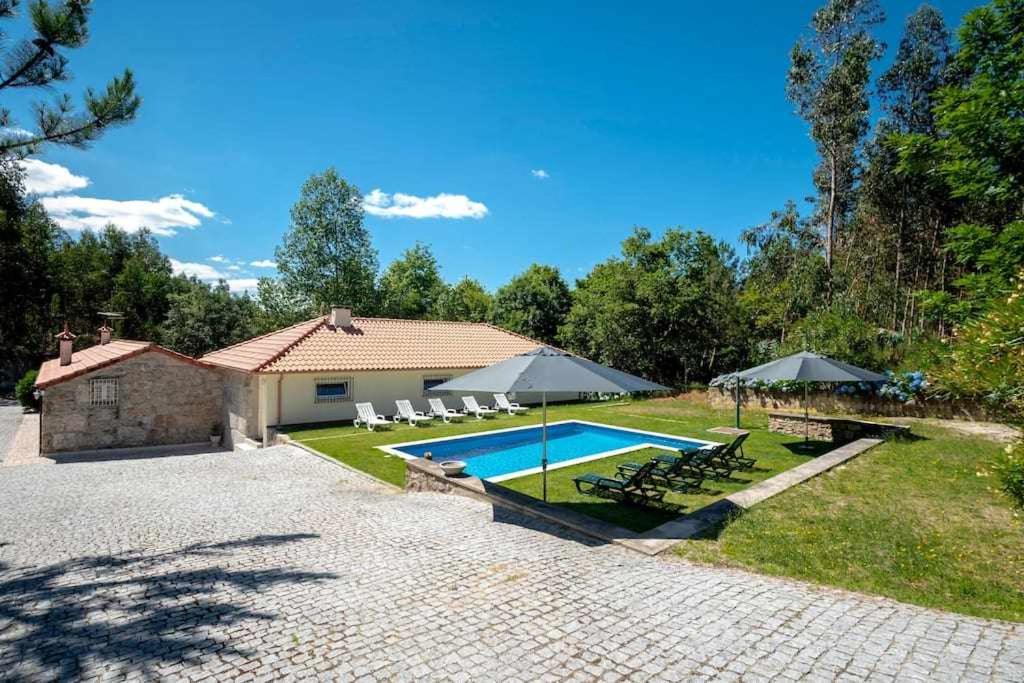 LamelasCasa do Pioledo Camélias de Basto的一座房子,设有一座带椅子和遮阳伞的游泳池