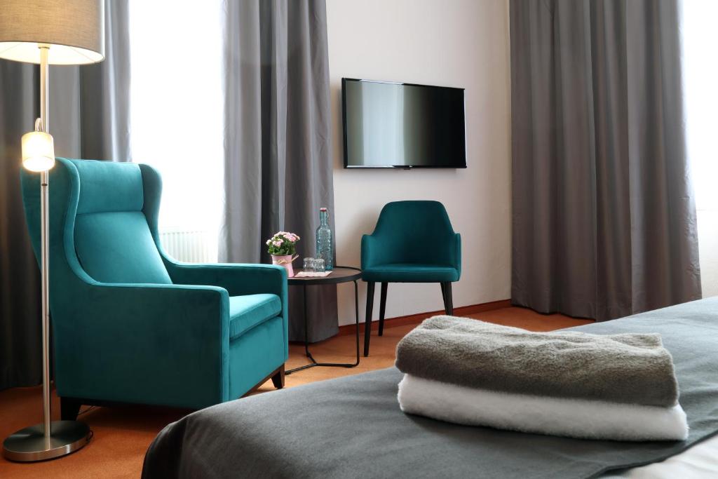 皮尔纳Hotel Sächsischer Hof的酒店客房配有1张床、2把椅子和电视。