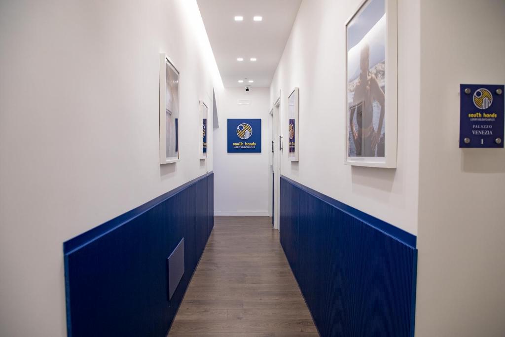 那不勒斯South Hands Luxury Rooms的拥有蓝色和白色墙壁和绘画的走廊