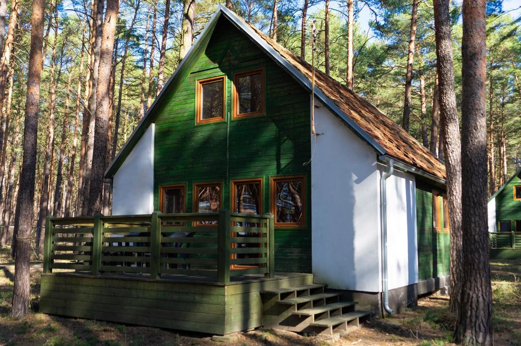 LubiatówSława Family Resort的树林中的一个绿色和白色的小房子