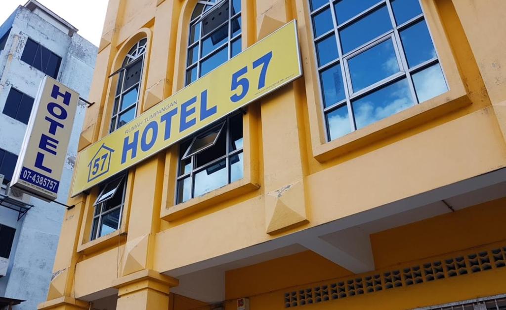 峇株巴辖Fifty Seven Inn的黄色建筑,上面有酒店标志