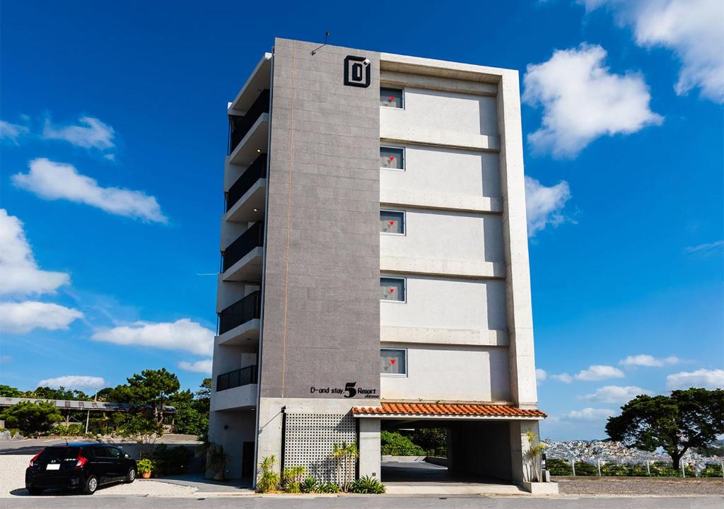 浦添D-and Stay 5 Resort Okinawa的一座高大的建筑,上面写着字母