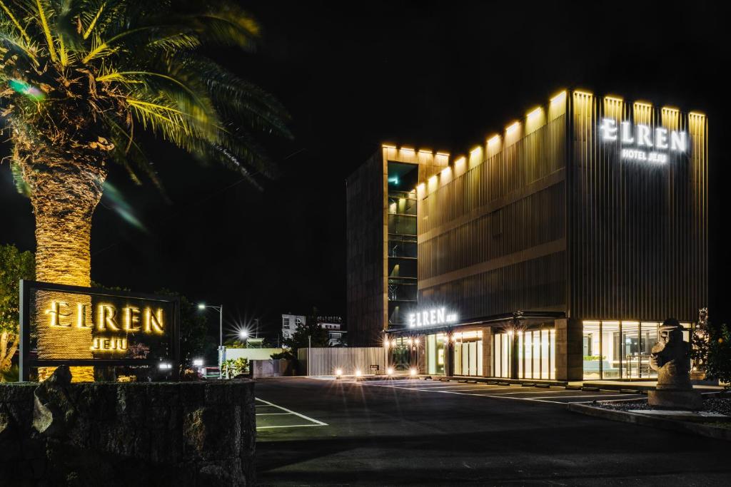 西归浦市Elren Hotel Jeju的一座在晚上有棕榈树的建筑