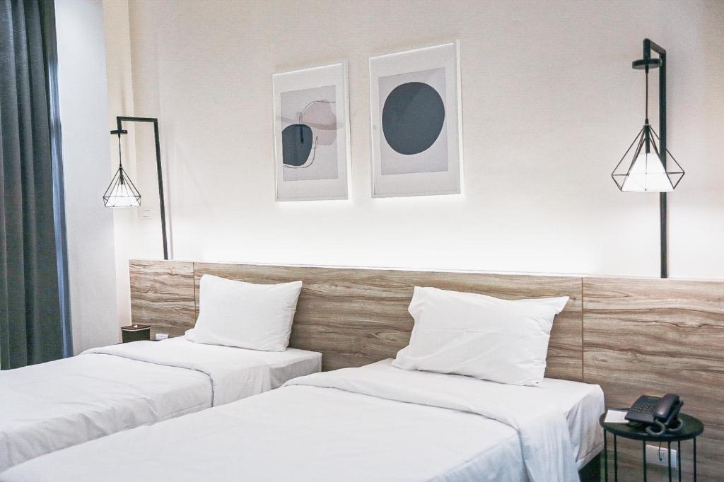 曼谷HOMITEL Bangkok的配有白色墙壁的酒店客房内的两张床