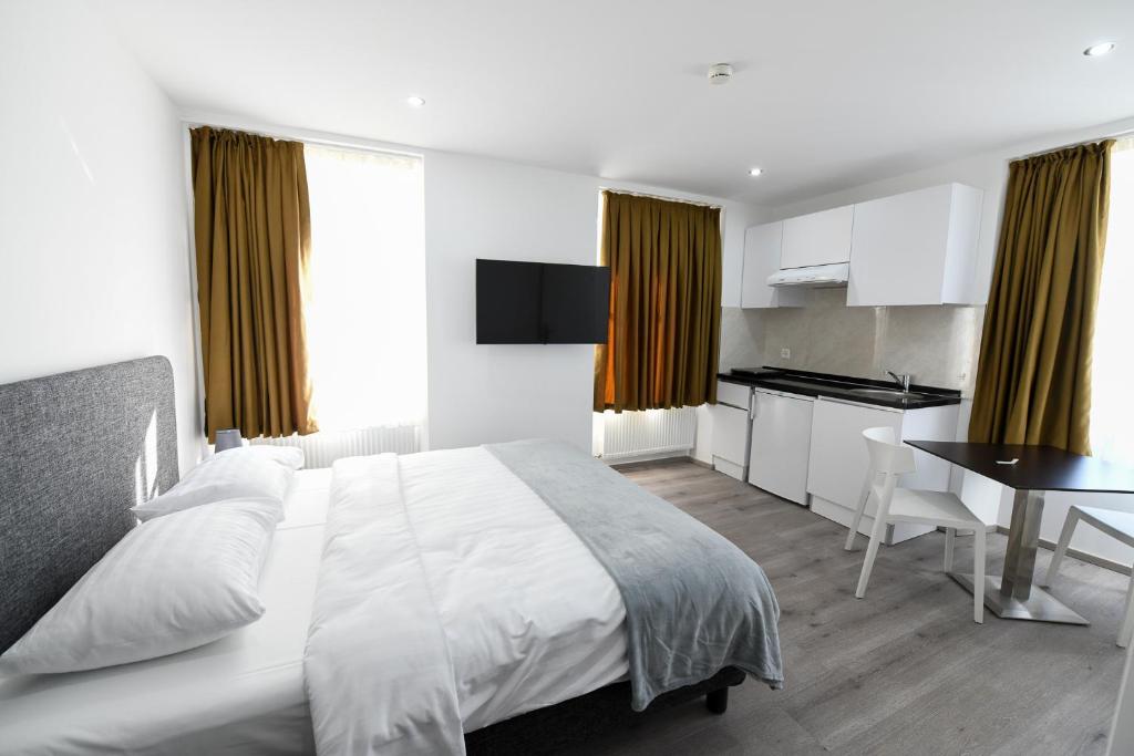 拉绍德封法国酒店的一间带白色床的卧室和一间厨房