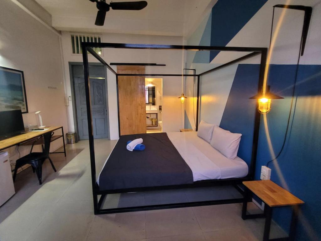 马德望THE PLACE Hostel & Rooftop Bar的一间卧室配有一张天蓬床、一张桌子和一台电视机