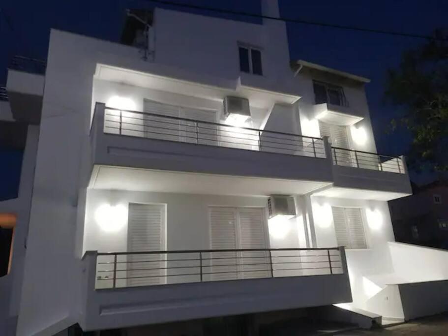Káto AlissósMelinas的白色的公寓楼,晚上设有阳台