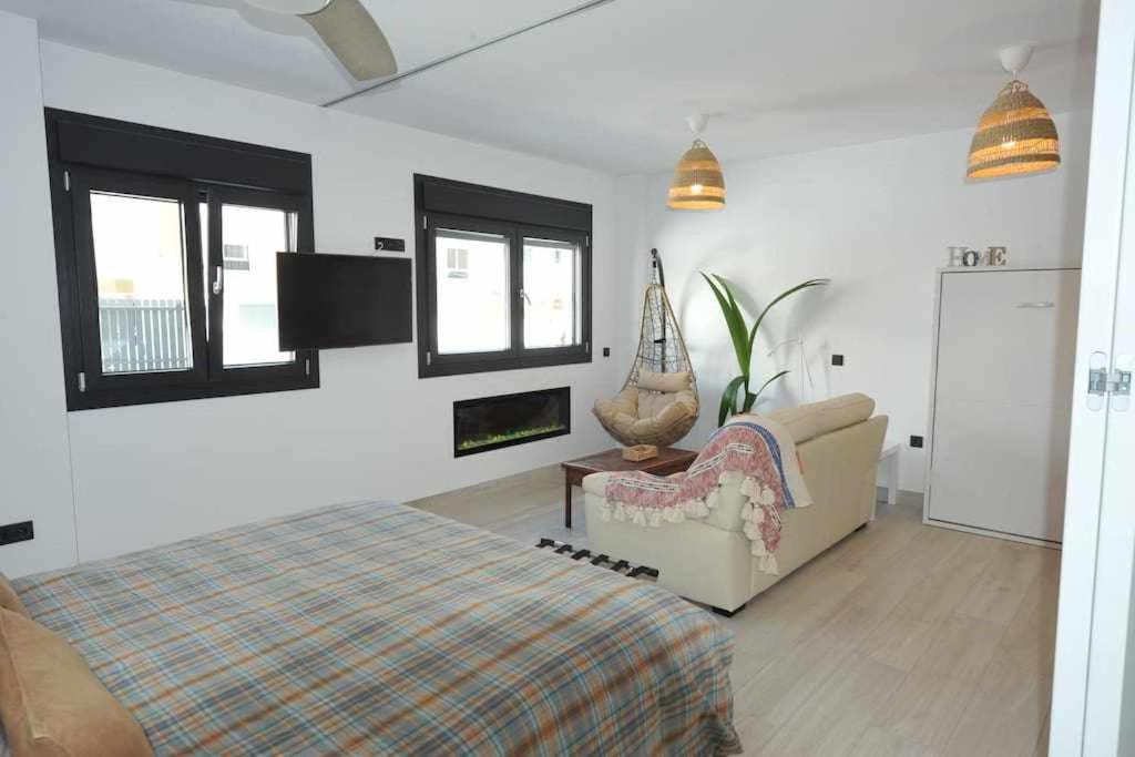加的斯Acogedor apartamento en la playa de Cádiz的一间卧室配有一张床、一张沙发和窗户。