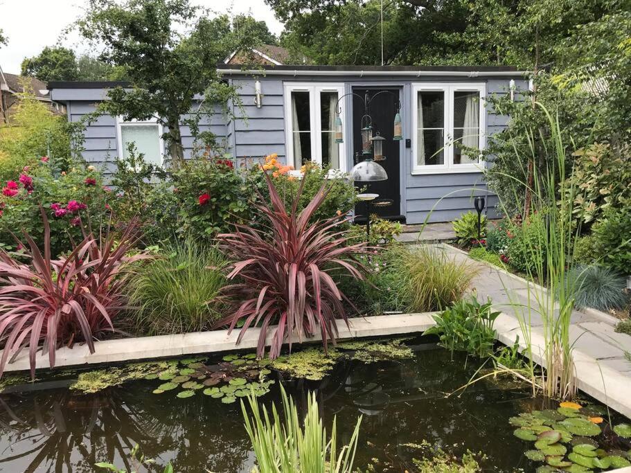 BroadstoneLovely detached garden chalet的前面有一个池塘的小房子